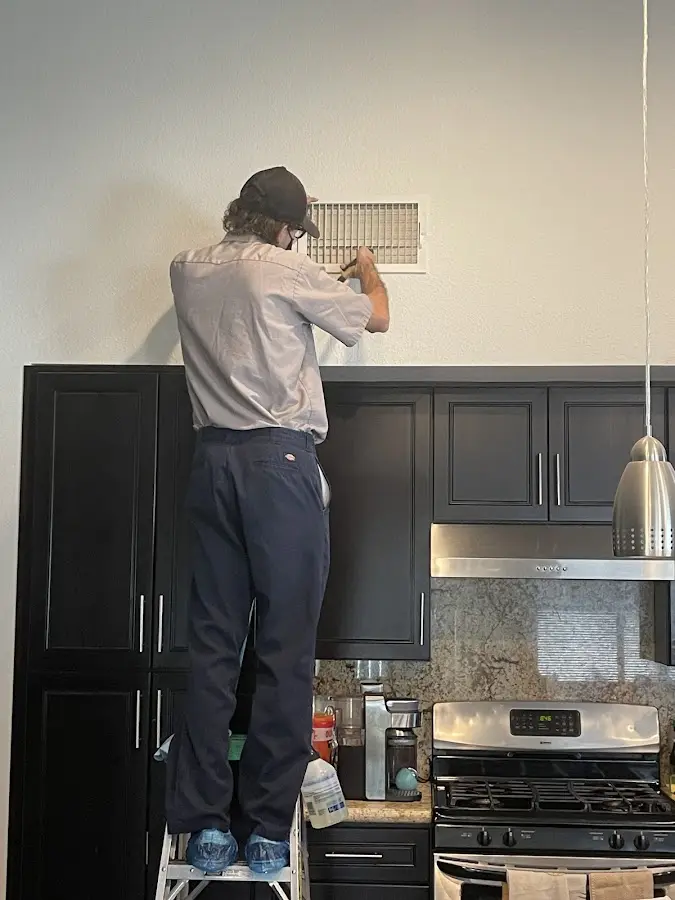 Technician inspecting an air vent during HVAC service in Newport News